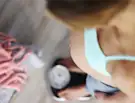 Pregnant woman in blue top checking weight on scale.