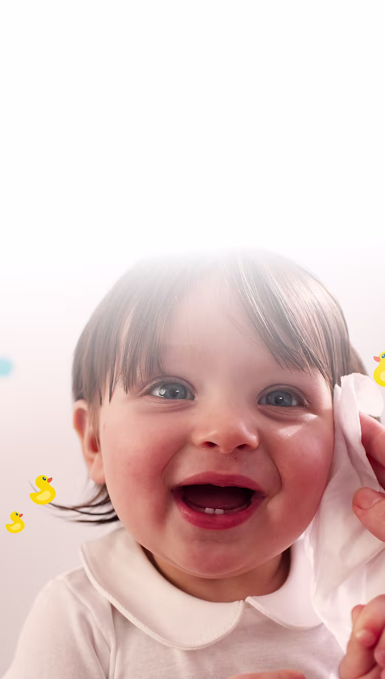 Eine Nahaufnahme des Gesichts eines Babys, während eine Hand sanft die Wange mit einem Pampers Fresh & Clean Feuchttuch reinigt.