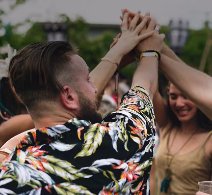 Group of friends raise their hands together in a cheerful high-five at an outdoor party.