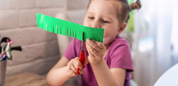 Niña recortando papel. Manualidades para niños
