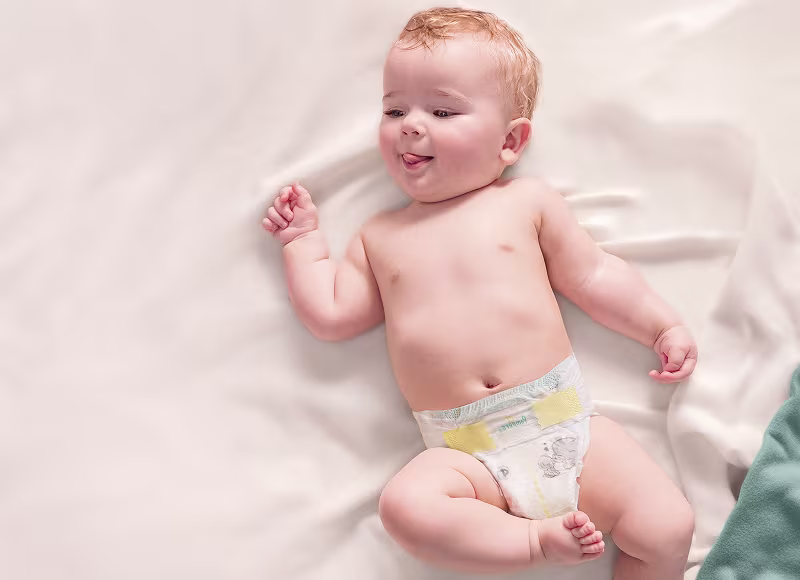 Baby som ligger på ryggen og har på seg en Pampers Premium Protection bleie Baby som ligger på ryggen og har på seg en Pampers Premium Protection bleie