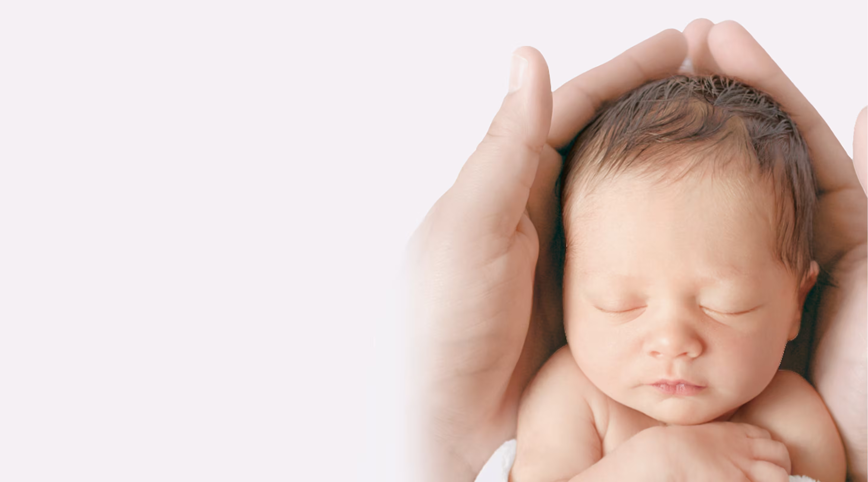 Una madre sonriente vestida con una bata de hospital sostiene a un bebé recién nacido dormido cerca de su pecho.