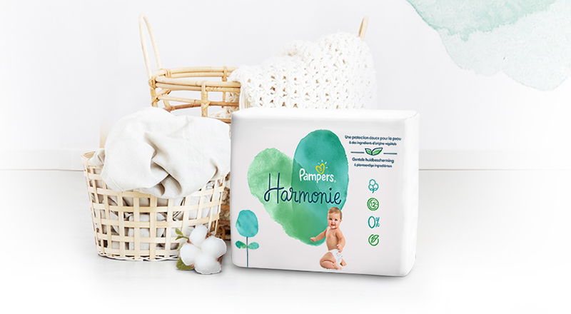 Interiorul unei camere cu decor în culori deschise în care se vede așezat pe o canapea pachetul de Pampers Harmonie.