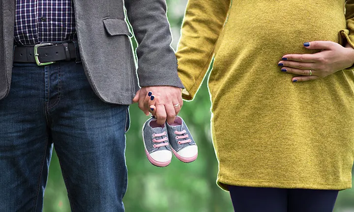 Hands and baby shoes pregnancy announcement idea