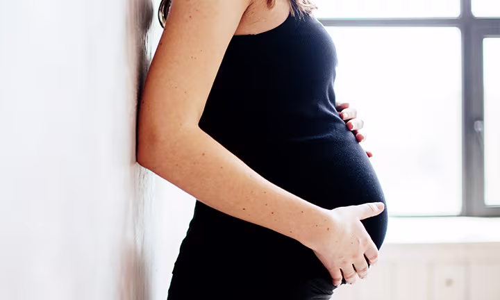 Schwangere Frau hält mit den Händen Ihren Bauch