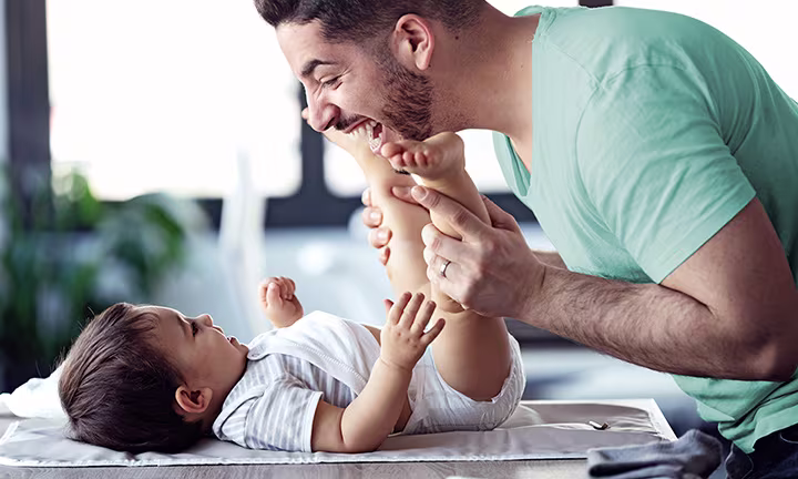 Vater spielt mit Baby auf Wickeltisch