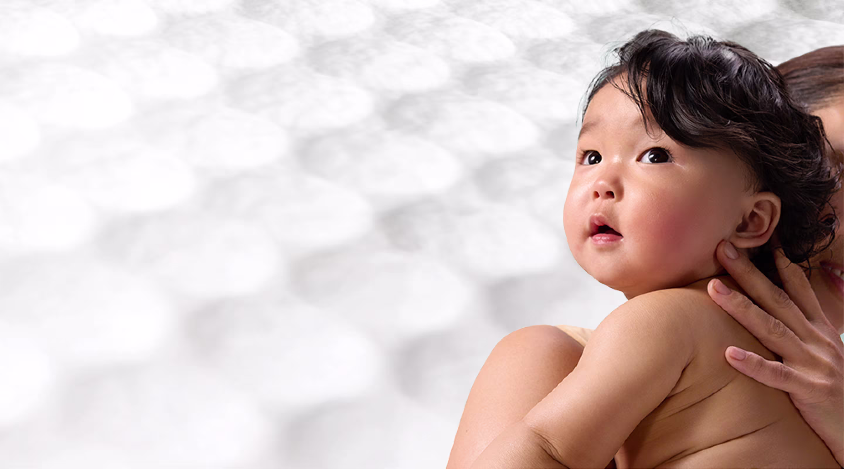 Uma mãe a segurar um bebé, com uma textura suave de toalhetes atrás