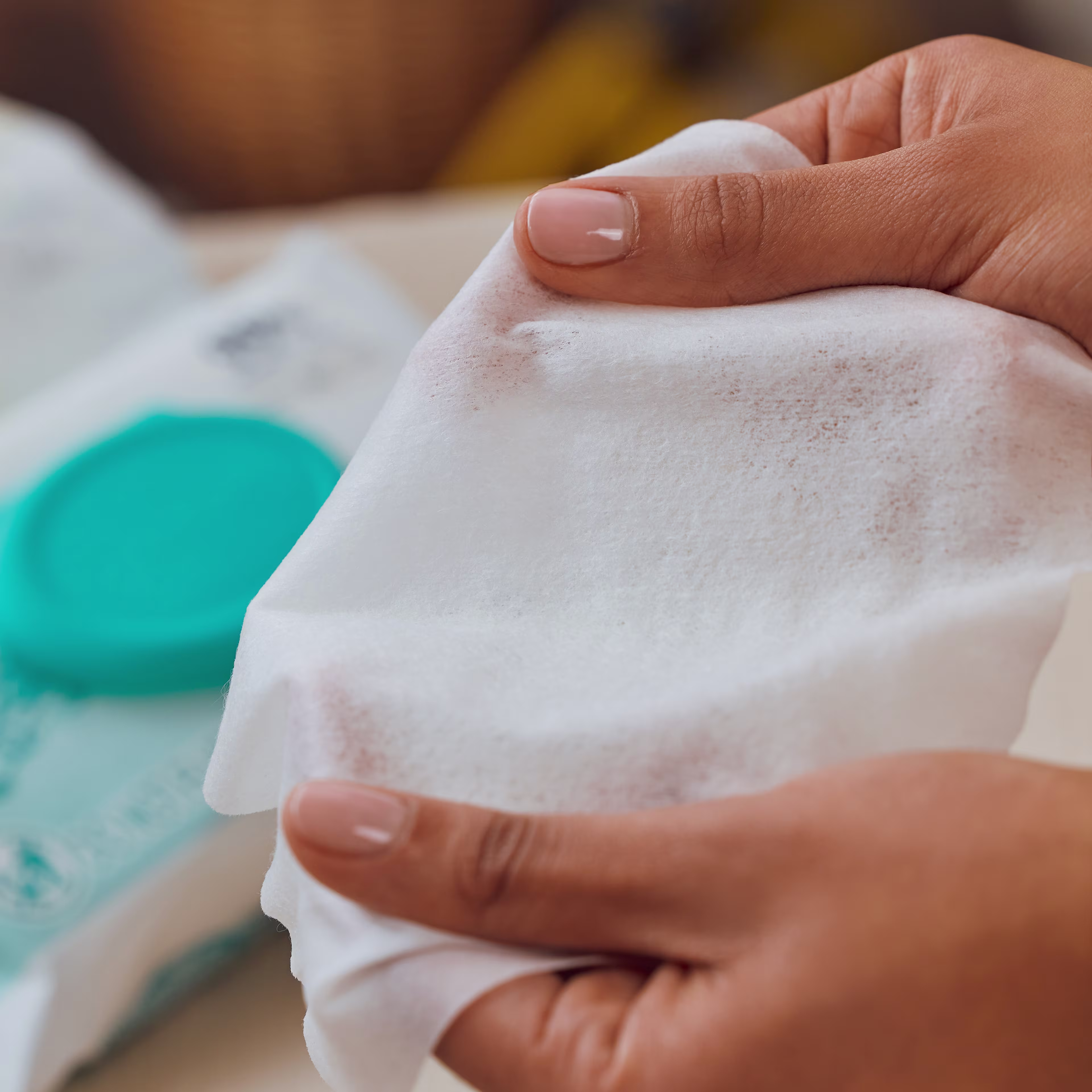 A close up of a Pampers Aqua Pure wipe being stretched by mom's hands A close up of a Pampers Aqua Pure wipe being stretched by mom's hands