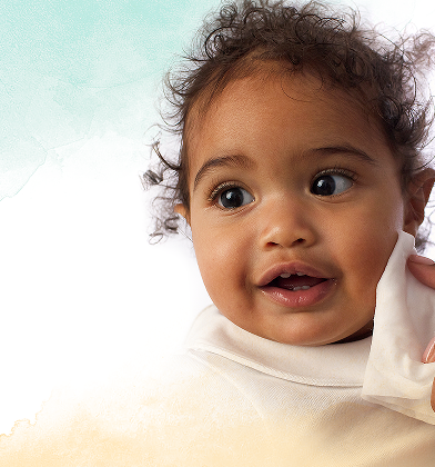 A close-up of a baby's face as a hand gently wipes their cheek with a Pampers Harmonie Protect & Care baby wipe.