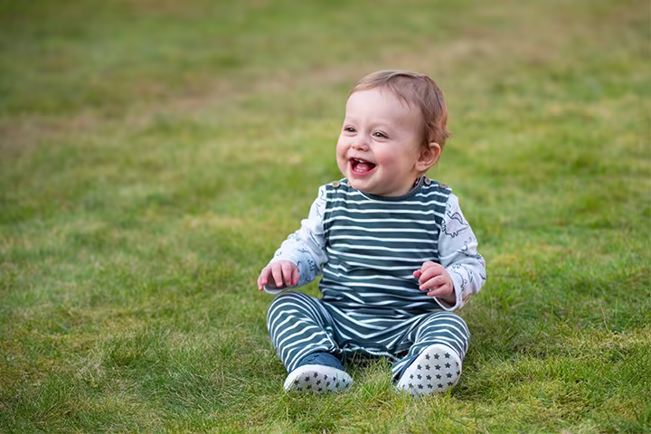 Bebeluș așezat pe iarbă.