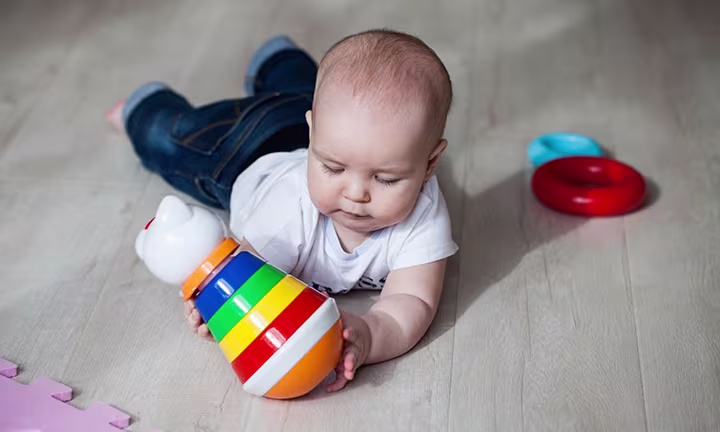 Baby spielt mit Spielzeug auf dem Boden liegend