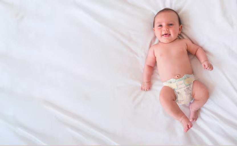 Ein Baby liegt auf einer Decke und trägt eine Pampers Premium Protection Windel.