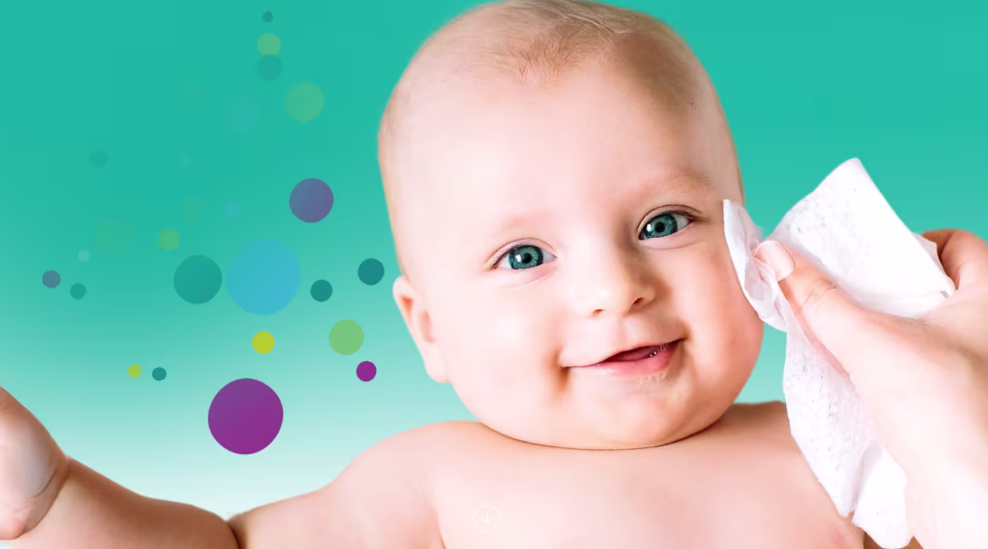 Un prim-plan al feței unui bebeluș în timp ce o mână îi șterge ușor obrazul cu un șervețel Pampers Harmonie Aqua.