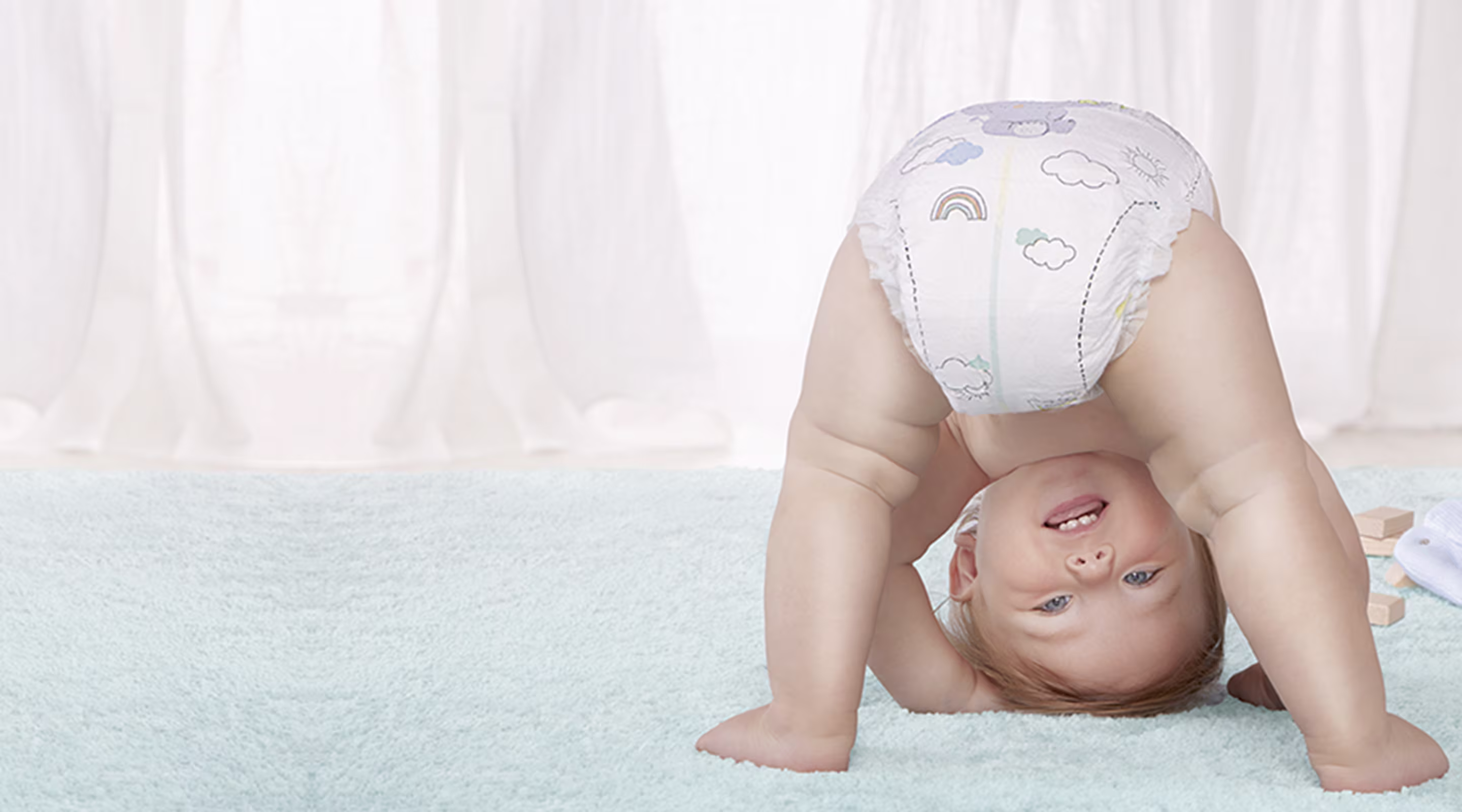 Ein Baby macht einen Handstand und trägt eine Pampers Premium Protection Windel.