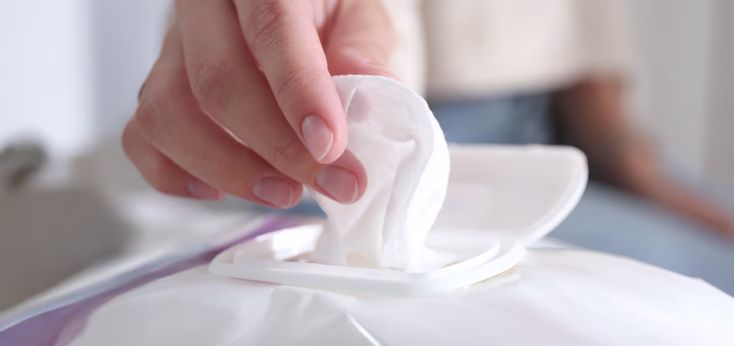 Hand pulling a baby wipe from a container, showing everyday hygiene and cleaning use.