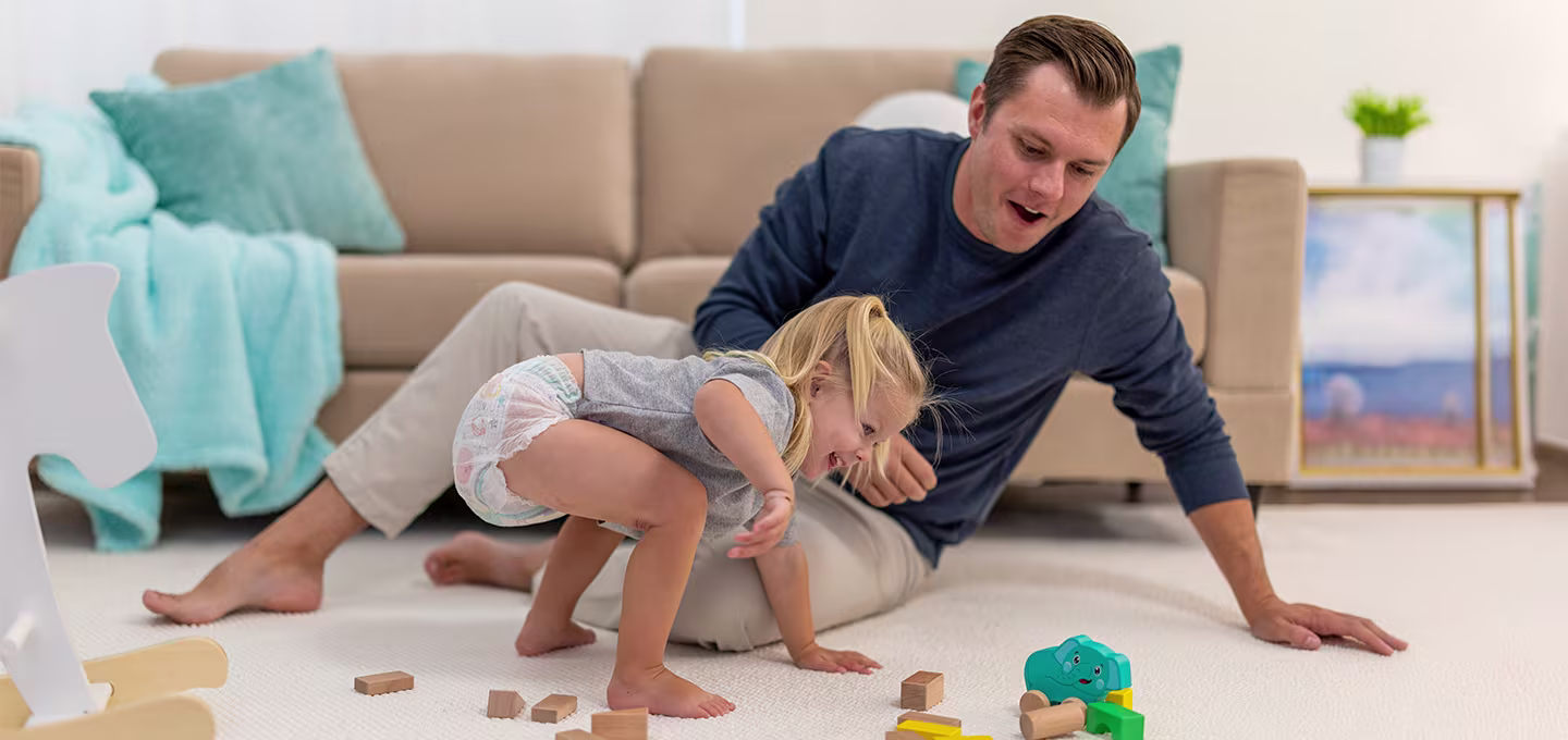 Una niña y su padre jugando en el suelo