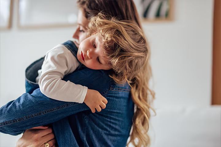  Νήπιο με σκυμμένο κεφάλι αγκαλιάζει γυναίκα​