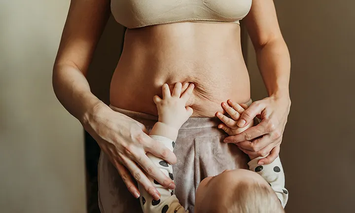 Ein Baby entdeckt Mamas bauch nach der Geburt