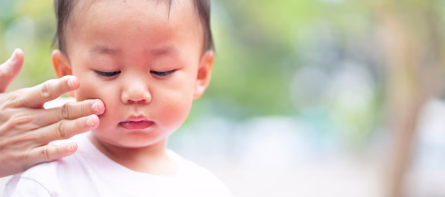 A toddler having sunscreen applied to their skin.