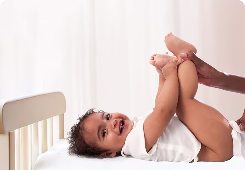 De baby ligt op zijn rug en wordt zachtjes gereinigd met een vochtig doekje.