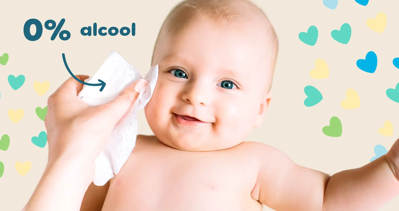 Imagine cu bebeluș pe fundal roz care este șters pe față cu șervețel Pampers.