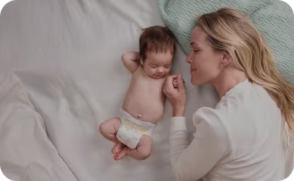Mãe deitada com o bebé que usa uma fralda Pampers
