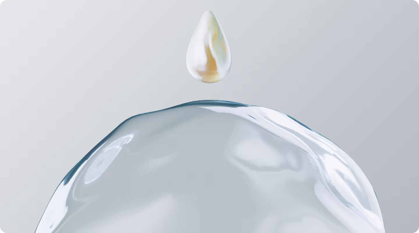 A lustrous, golden drop of serum is suspended above a clear, pure drop of water.