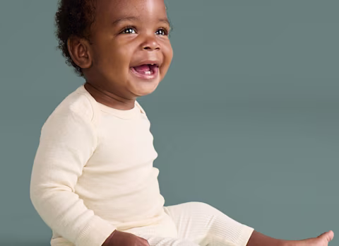 Baby sitting up on sage background Baby sitting up on sage background