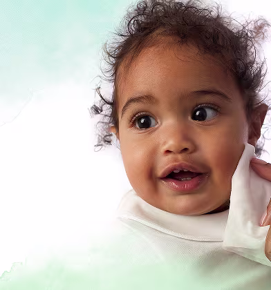 Um close-up da cara de um bebé enquanto uma mão lhe limpa suavemente a bochecha com uma toalhita Dodot Pure Calma & Protege. Um close-up da cara de um bebé enquanto uma mão lhe limpa suavemente a bochecha com uma toalhita Dodot Pure Calma & Protege.