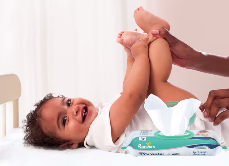 Baby liegt auf dem Rücken und wird sanft mit einem Feuchttuch gereinigt.