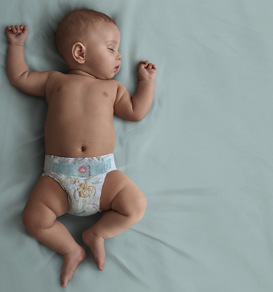 A baby wearing a Pampers nappy, sleeps on their back on a teal blanket