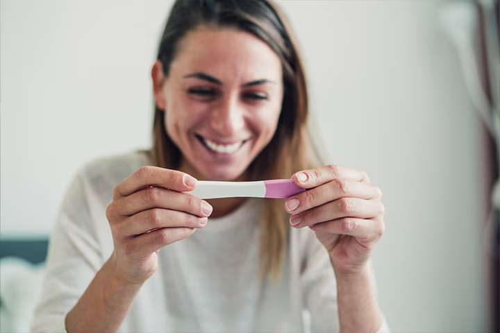 Femeie care ține în mână un test de sarcină.
