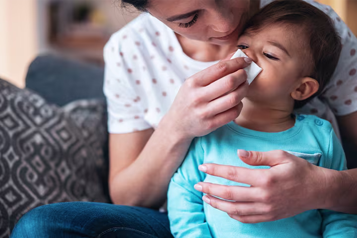 Παιδάκι φυσάει τη μύτη του με τη βοήθεια της μαμάς του
