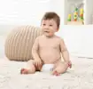 Baby sitting on a rug in diapers