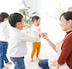 Teacher interacting with smiling toddlers in a bright classroom, encouraging play and learning.