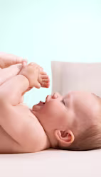 En närbild av ett spädbarns ansikte medan en hand försiktigt torkar deras kind med en Pampers Harmonie Aqua-våtservett.