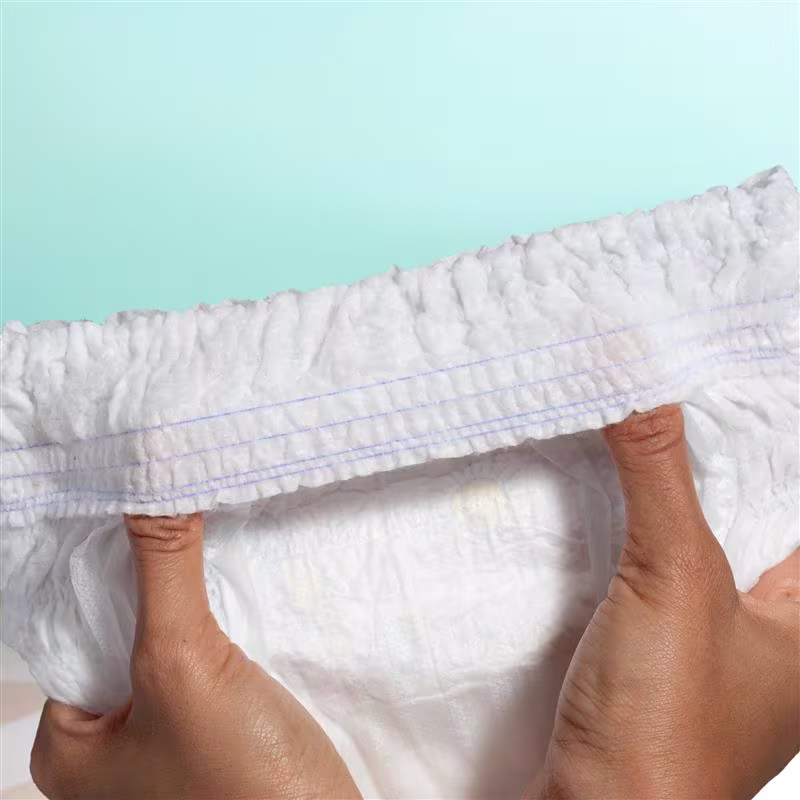 Two hands hold an open diaper with thumbs under the blowout barrier