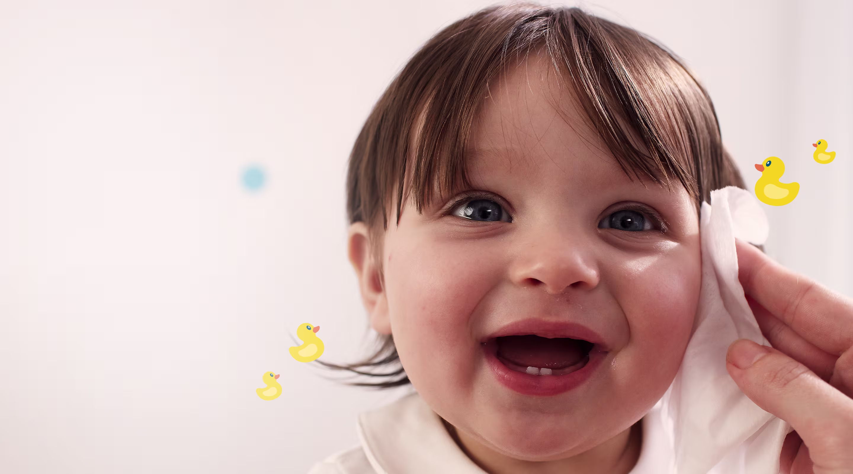 Un primer plano de la cara de un bebé mientras una mano le limpia suavemente la mejilla con una toallita Dodot Siempre Limpio.