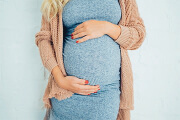 Pregnant woman in a cozy sweater gently cradling her belly.