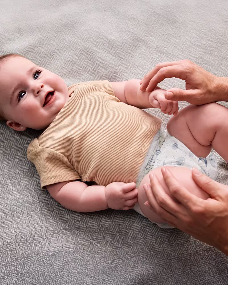 Mãe colocando uma fralda nova em seu bebê.