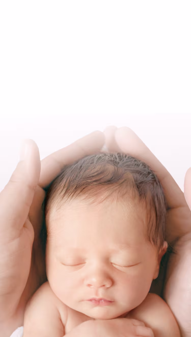 2 mains tiennent doucement la tête d’un bébé nouveau-né.