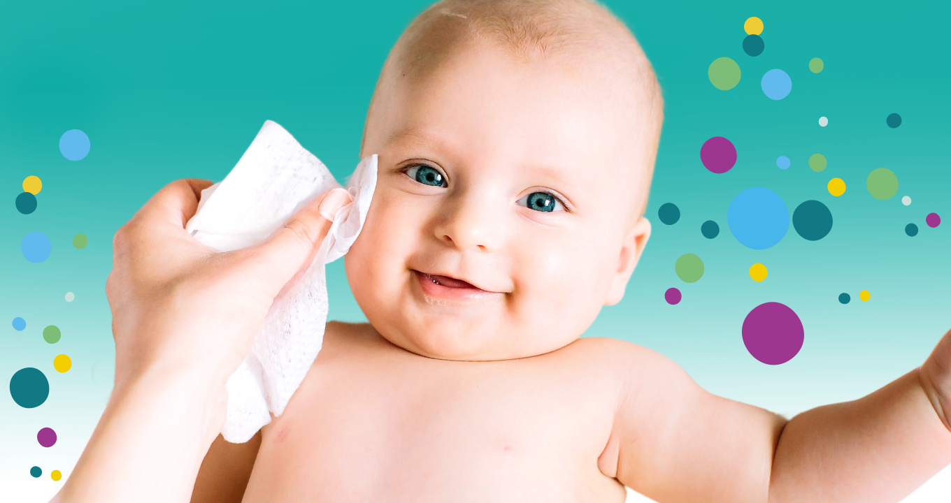 Lächelndes Baby dem sanft mit Feuchttuch über die Wange gewischt wird