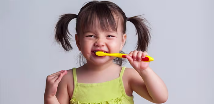 Criança com escova de dente na boca