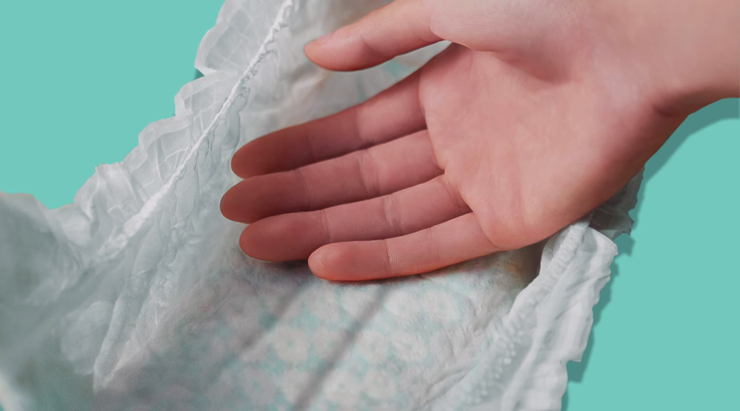 Ultra Suave. Mão tocando a fralda macia