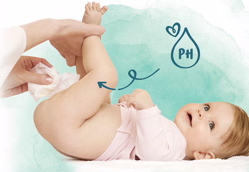 Vauva makaa selällään samalla kun henkilö pyyhkii vauvan takapuolta kosteuspyyhkeellä.