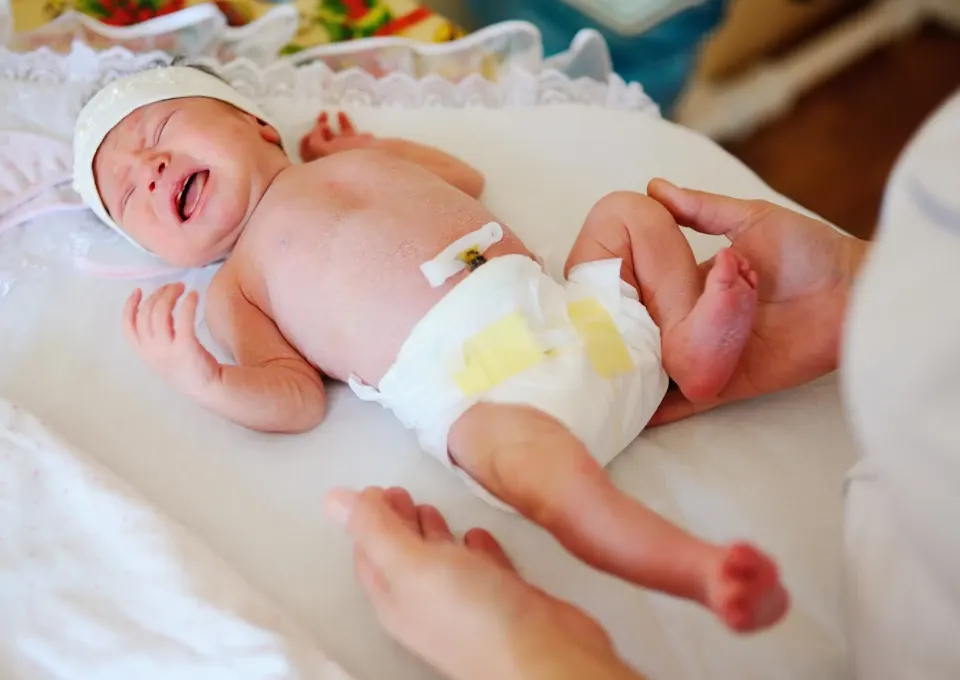 Mamá cambiando pañal a bebé con cordón umbilical