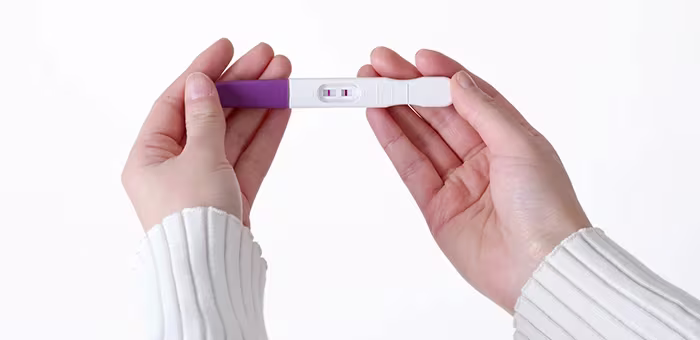 Mujer con primeros síntomas de embarazo viendo prueba de embarazo