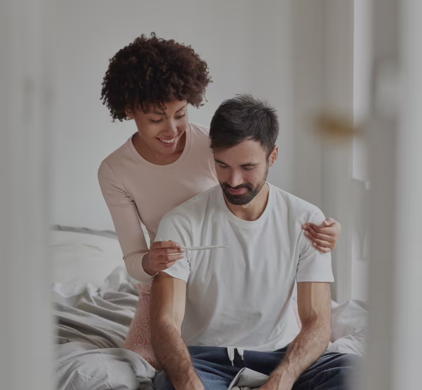 A mom showing a pregnancy test to her partner looking happy