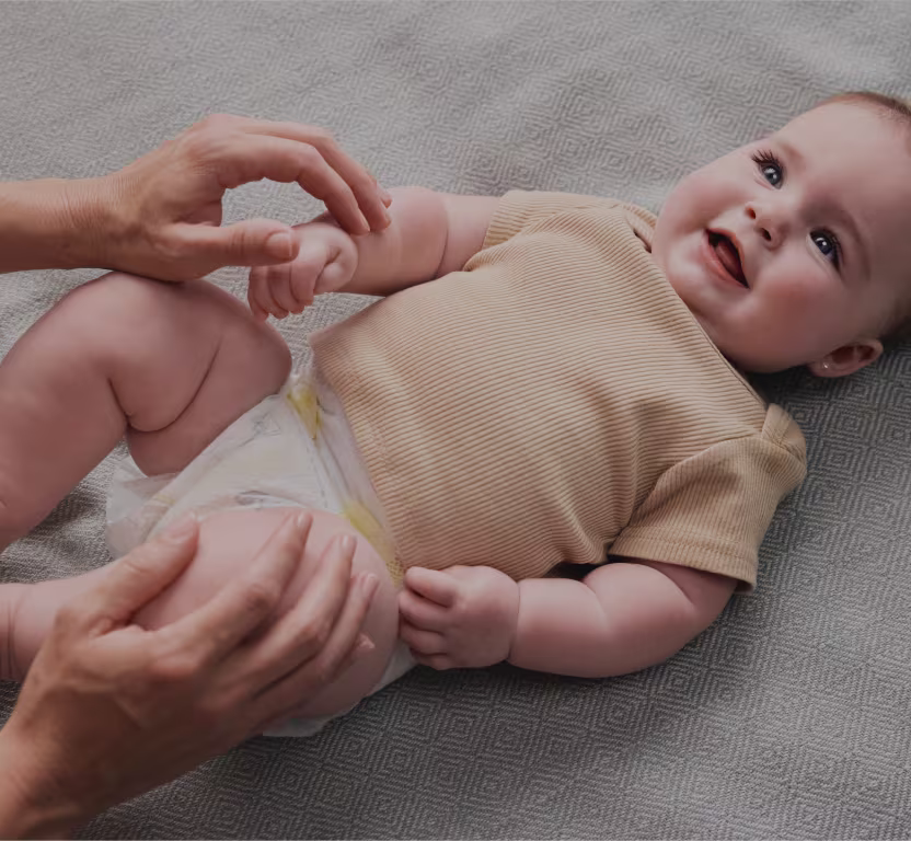 Closeup of baby lying on a changing table wearing pampers diapers, smiling