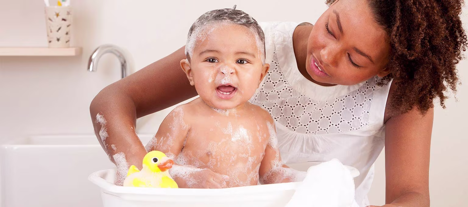 A mother bathing her baby using a bath seat for support.